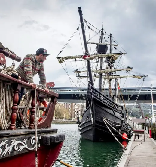 Una persona observa la réplica de la Nao Victoria embarcando en el muelle. Extraida de Araba Press.