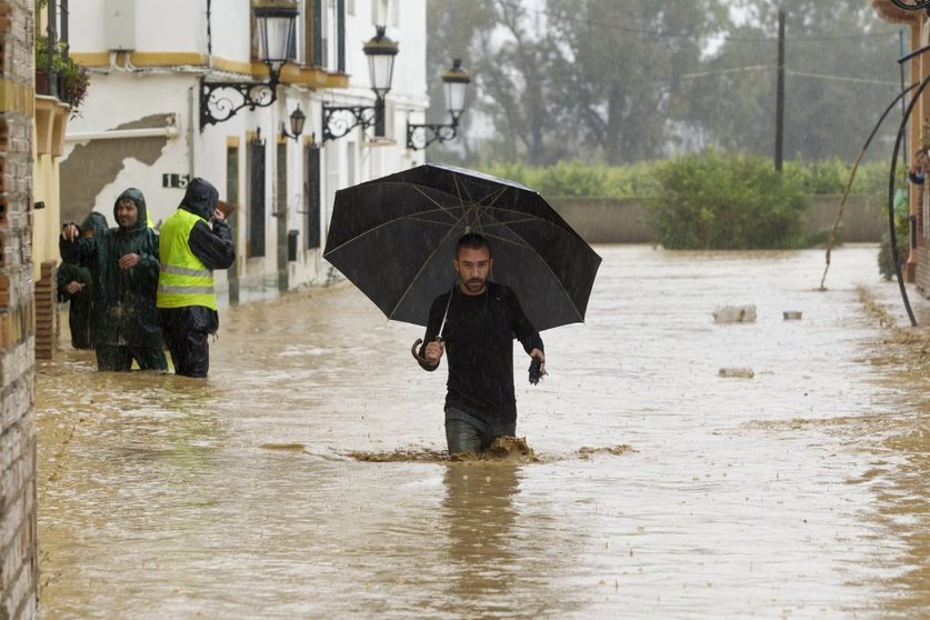 Hombre caminando por una calle inundada. El agua sobre pasa sus rodillas.
