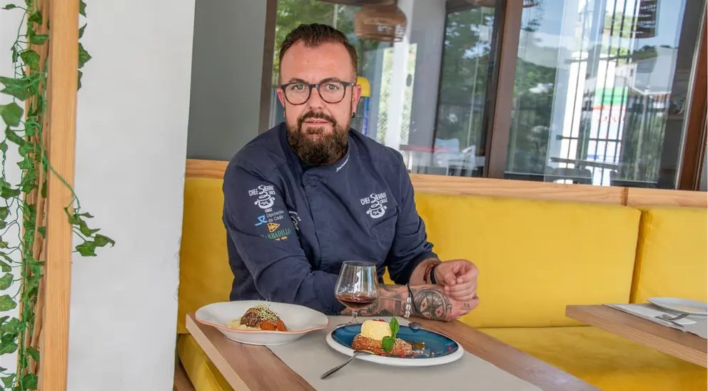 El cocinero José Antonio Morales sentado en su restaurante con un plato de carrillera y otro de torrija