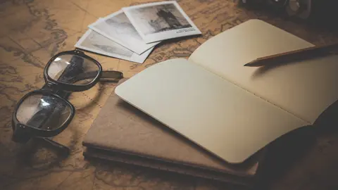 Gafas, libretas y fotograf&iacute;as sobre un mapa.