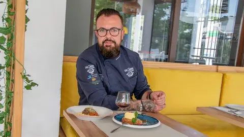 El cocinero Jos&eacute; Antonio Morales sentado en su restaurante con un plato de carrillera y otro de torrija