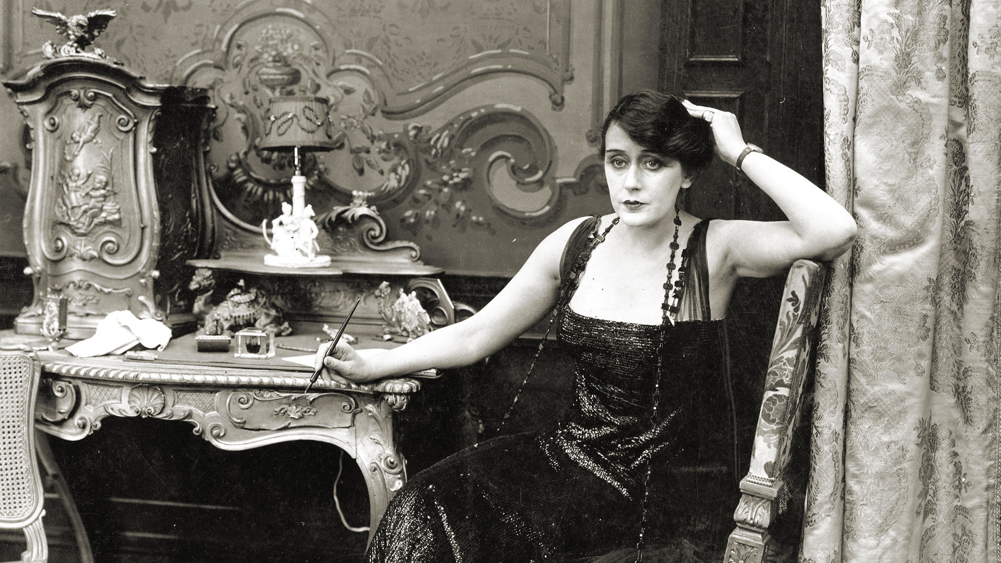 Alice Guy Blaché posando sentada junto a su escritorio.